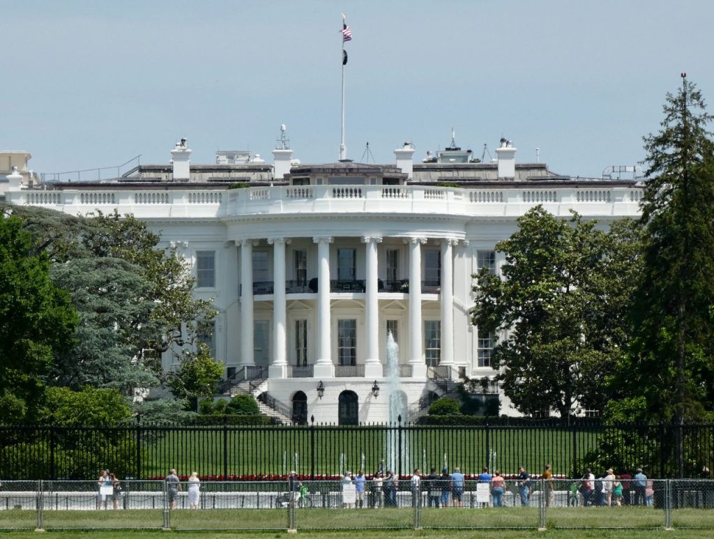 The White House in Washington DC, with tourists viewing from the lawn.