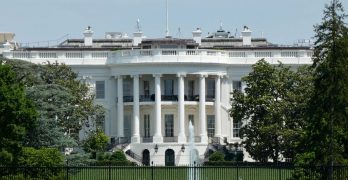 The White House in Washington DC, with tourists viewing from the lawn.