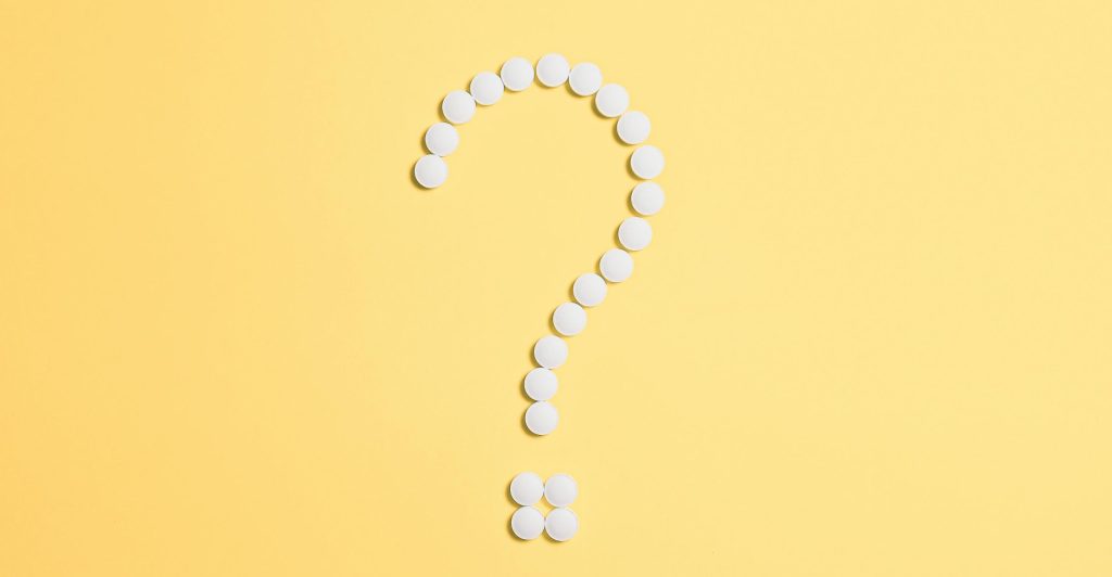 White pills arranged into a question mark shape on a vibrant yellow background.