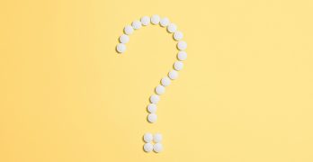 White pills arranged into a question mark shape on a vibrant yellow background.