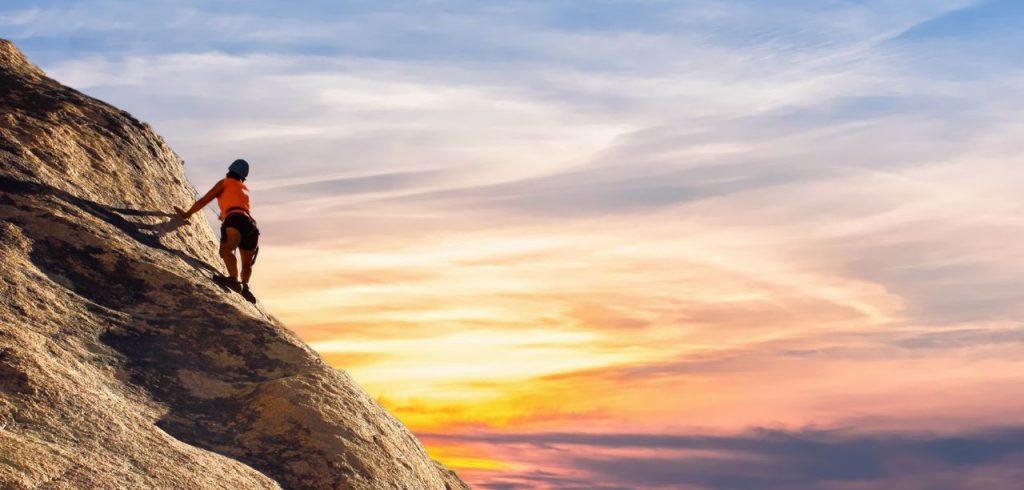 Climber conquers rock face at sunset, embracing the thrill and challenge.