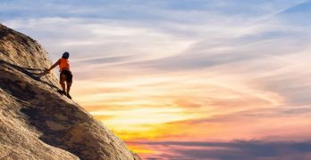 Climber conquers rock face at sunset, embracing the thrill and challenge.