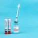 Vaccine vial and blood test tubes labeled COVID-19 on a blue surface, representing healthcare progress.