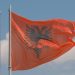 Albanian flag waving against a modern city backdrop, symbolizing national pride.