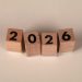 Wooden cubes forming the year 2026 on a neutral background.